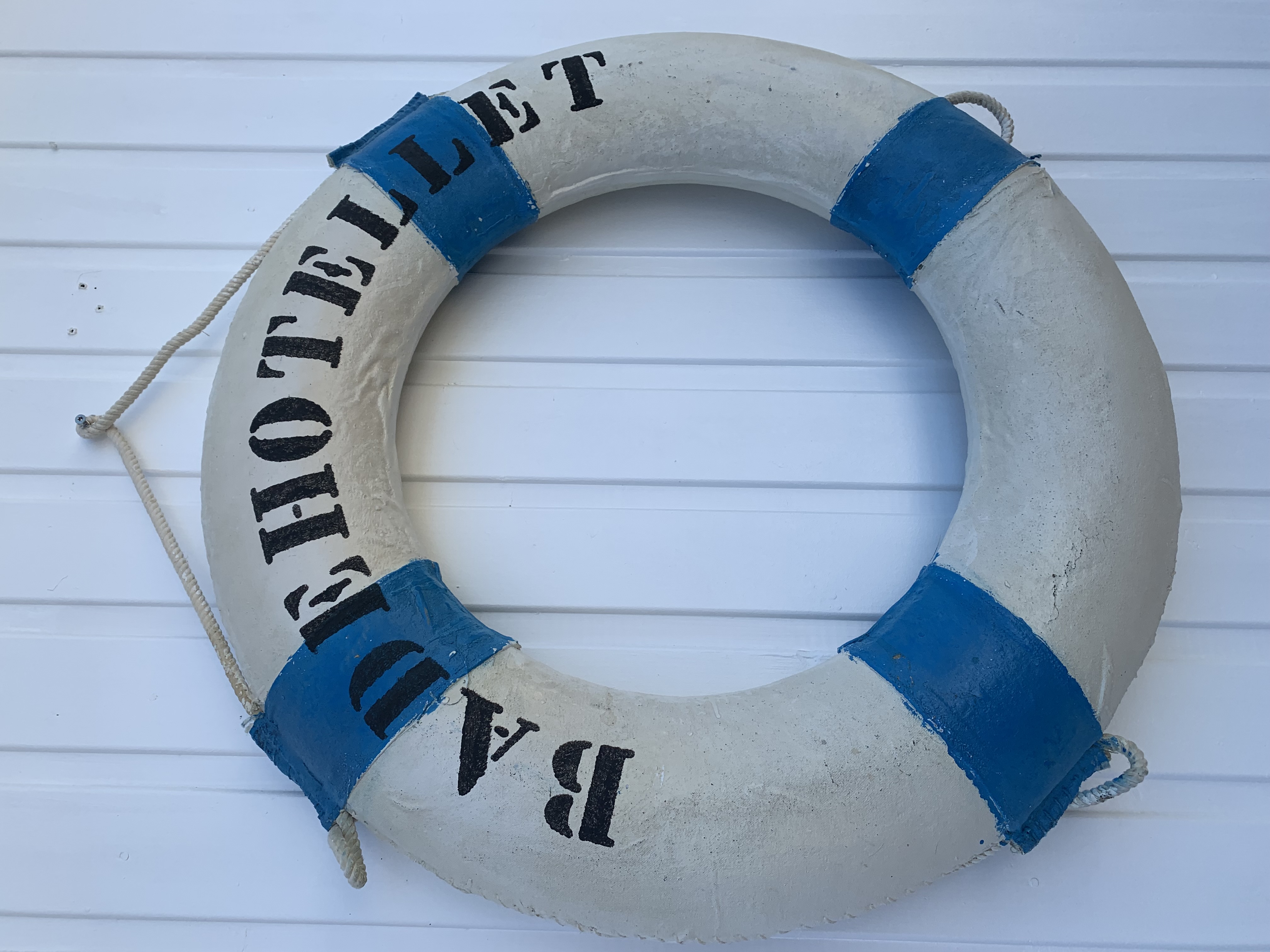 Hvit og blå redningsbøye med Badehotellet som veggpynt