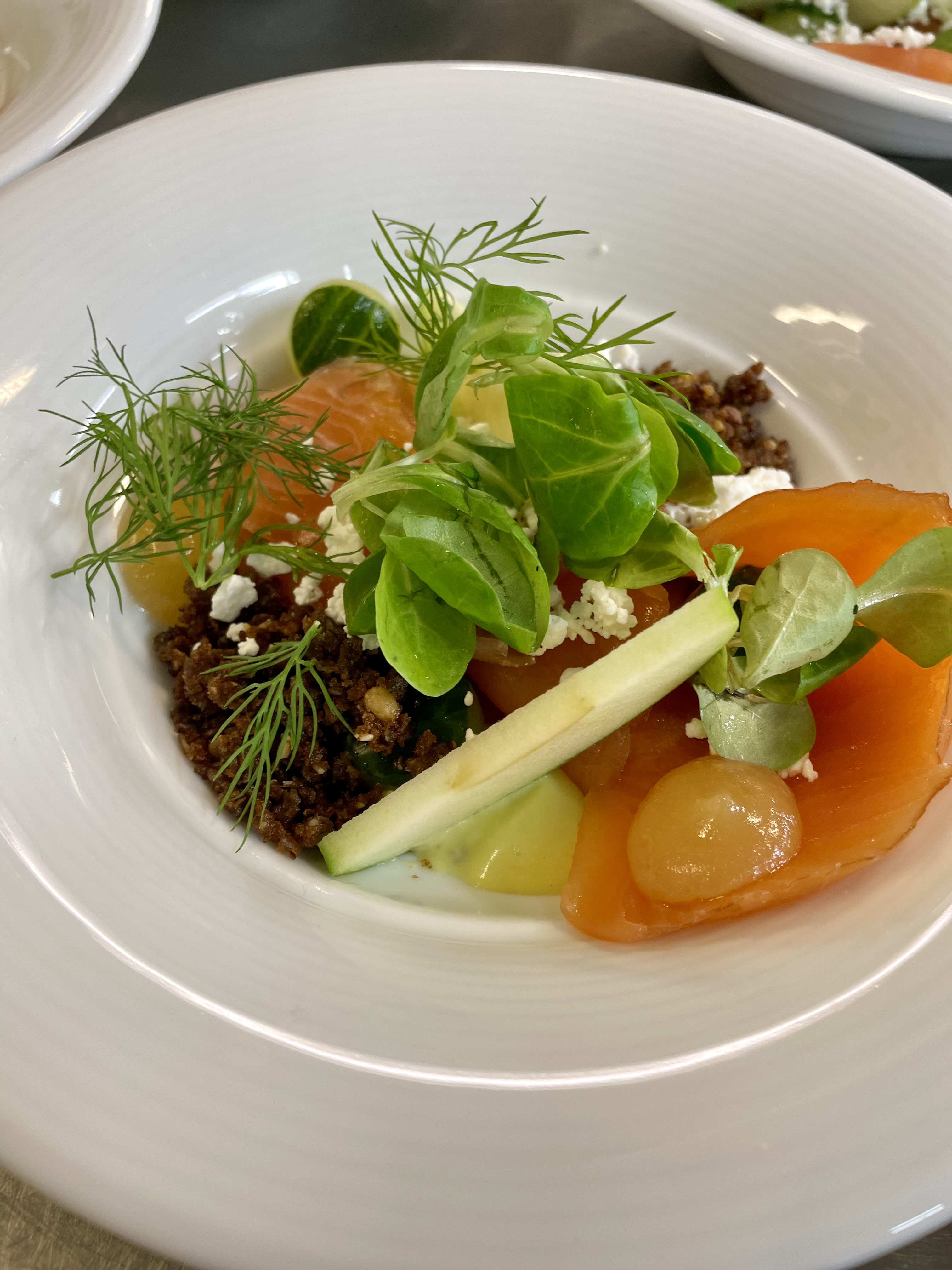 -En kokk heller saus over kjøtt og grønnsaker på en ferdig tilberedt rett med pommes frites i liten metallbøtte -